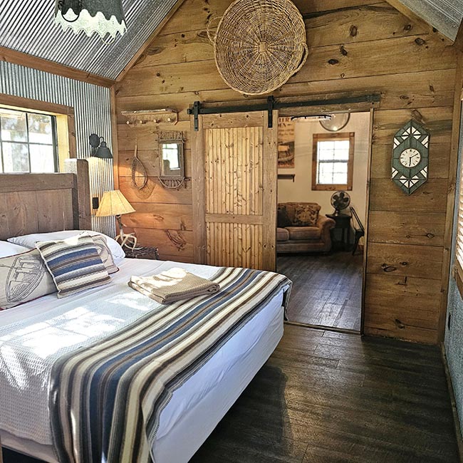 Rustic Creekside Cabin loft bedroom with a queen bed, barn style sliding door, and cozy cabin decor at Bear Creek Cabin Resort in Walnut Shade, Missouri